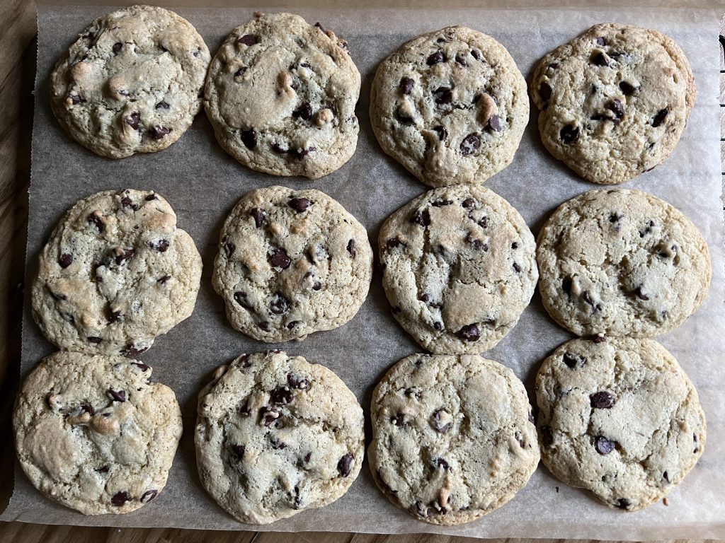 sourdough chocolate chip cookies on a baking rack with parchment paper.chocolate chip cookies with sourdough starter. chocolate chip sourdough cookies